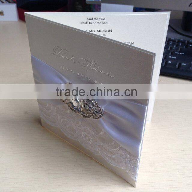 Attractive white lace wedding invitation cards with ivory ribbons and rhinestone brooches