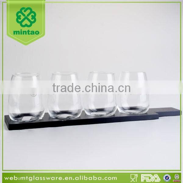 Clear stemless beer glass cup with black wooden rack and plate