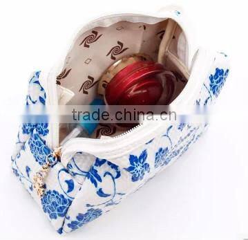 Blue and white diamond pattern cosmetic bag in hand