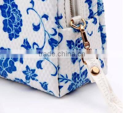 Blue and white diamond pattern cosmetic bag in hand