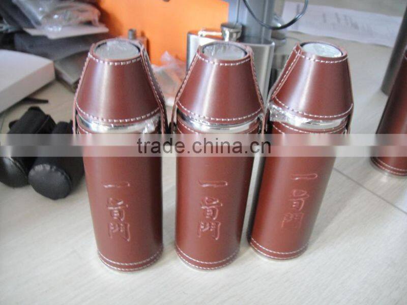 Cylindrical shape and suture and leather wrapped bottle and 2 glasses