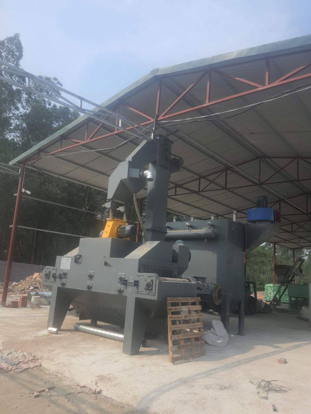 What is the working principle of the track through shot blasting machine?