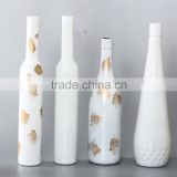 white glass bottle with gold