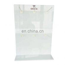 Розничный магазин. Индивидуально изготовленное белое акриловое стенд для демонстрации чулков с держателем пластиковых крючков