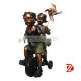 Metal Chiildren Satues Playing Windmill by Bike thumbnail-1