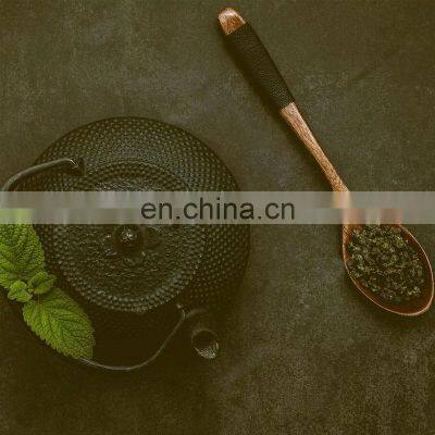 Black Cast Iron Tea Pot With Herbal Tea Set up Dark Stone Background