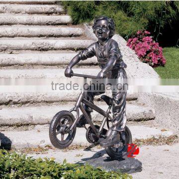 Bronze cute boy statue by bike playing in backyard