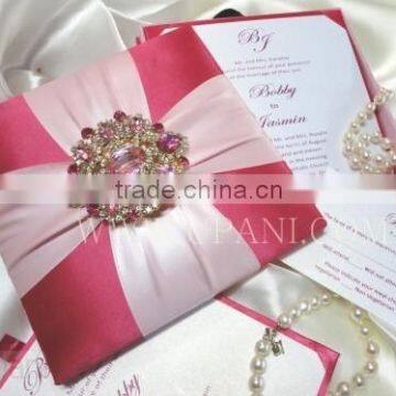 Pink silk wedding invitation box with a large brooch