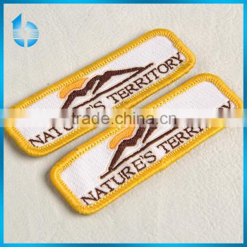 Overlocked sewing woven badge with fushing cementing on backside for hiking clothing