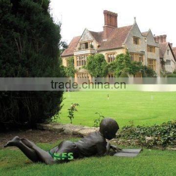 Bronze grovelling boy reading statue