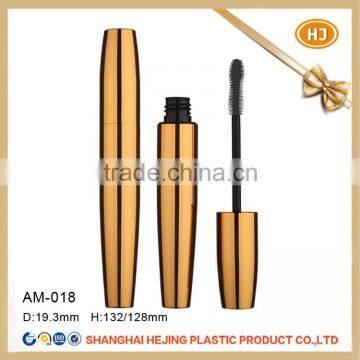 Empty shiny gold mascara tube with different brush