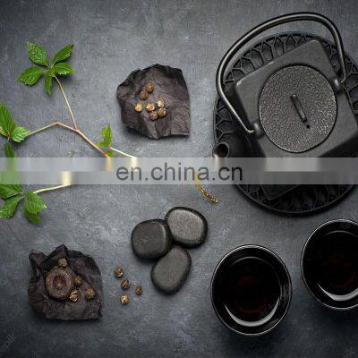Black Cast Iron Tea Pot With Herbal Tea Set up Dark Stone Background