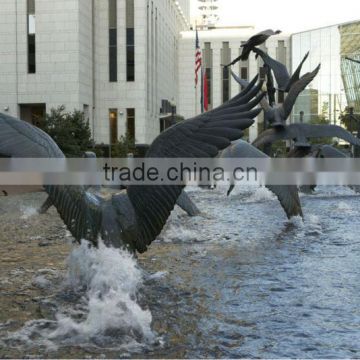 Lots of bronze birds flying in water sculpture