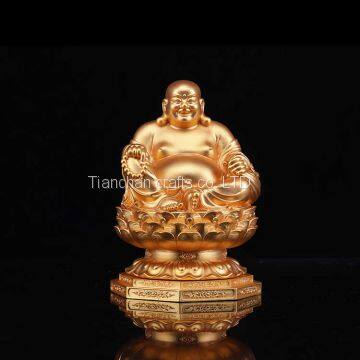 The golden happy buddha stuatue is seated in a double lotus base show his smiling and big belly