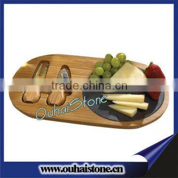 Oval wood chopping board with round slate cheese serving set and knife