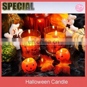 Halloween glass candle with pumpkins on black background