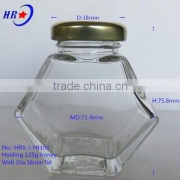 holding 125g Honey glass jar with golden lid