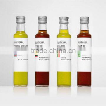 small round and clear glass olive oil bottle with aluminum cap with label