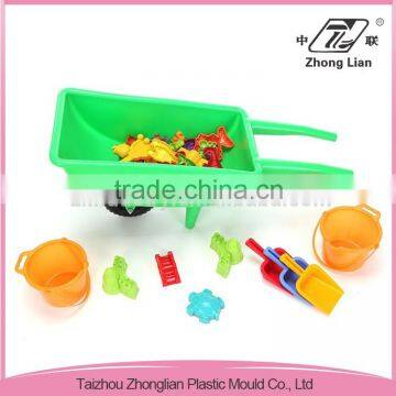 Children play green plastic wheelbarrow outdoor sandy beach toys