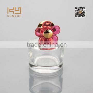 small round glass perfume bottle with red flower cap