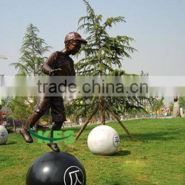 Bronze little boy standing in ball statue