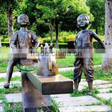 Bronze children playing seesaw statue